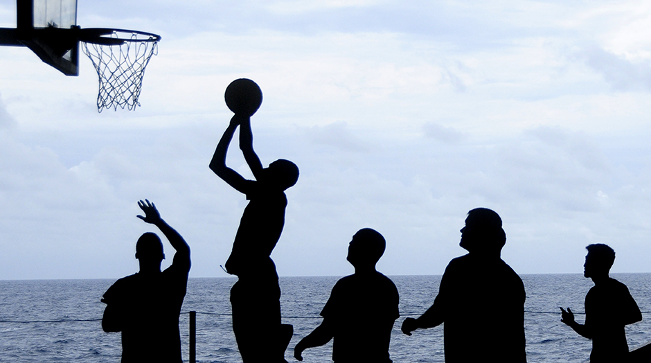 group of people playing basketball by the sea