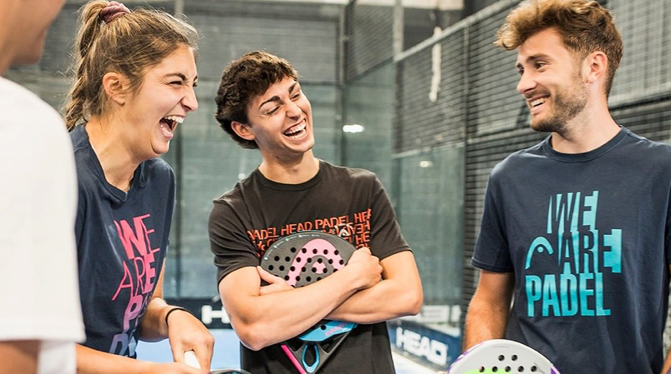 grupo de amigos charlando y riendo en la pista de padel con raquetas