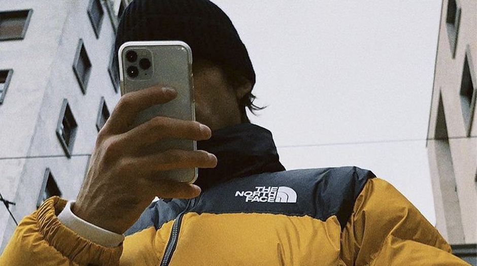 homem a tirar foto com casaco amarelo e preto da the north face