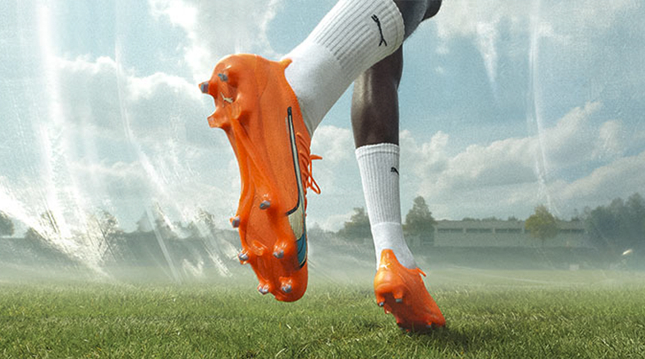 chuteiras cor de laranja em pes com meias brancas em campo de futebol