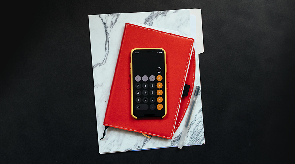 telemovel com calculadora aberta emc cima de caderno com capa vermelha
